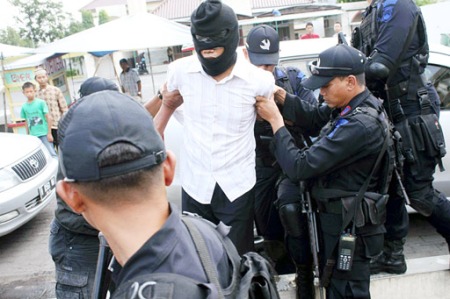 Indonesian law enforcement detain a hooded jihadist